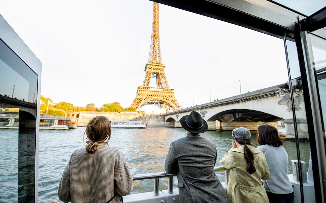 Tourists on Seine River Cruise viewing Eiffel Tower in Paris.