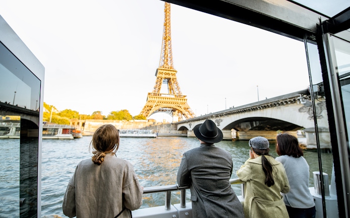 Tourists on Seine River Cruise viewing Eiffel Tower in Paris.