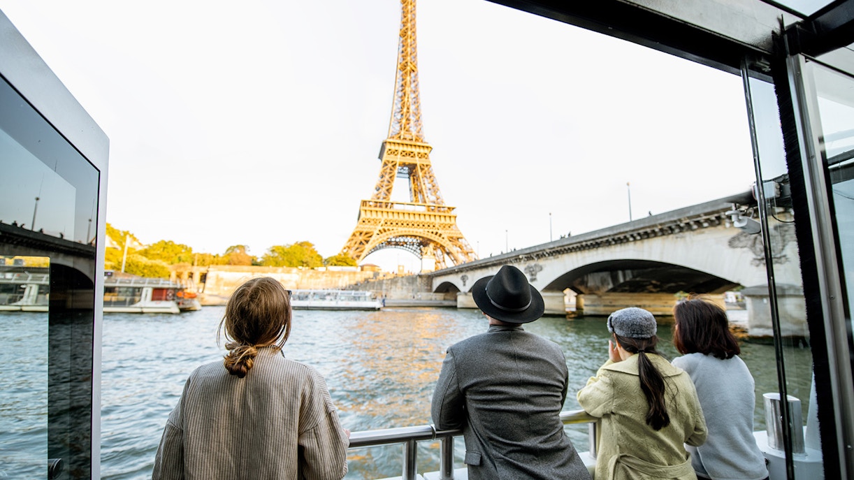 Tourists enjoying the seine river cruise in evening wearing warmer clothing