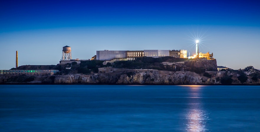 Alcatraz Island with lighthouse illuminated at dusk, San Francisco Bay.