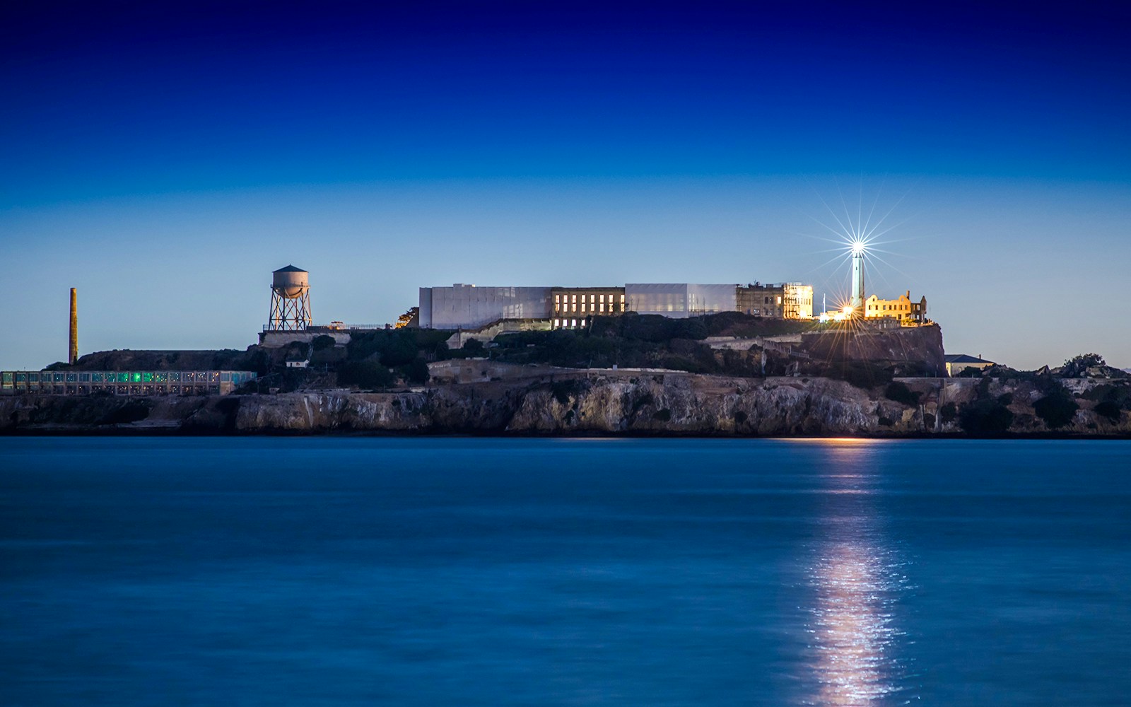 Alcatraz Island with lighthouse illuminated at dusk, San Francisco Bay.