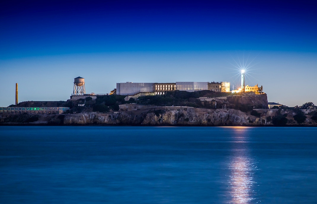 Alcatraz Island with lighthouse illuminated at dusk, San Francisco Bay.