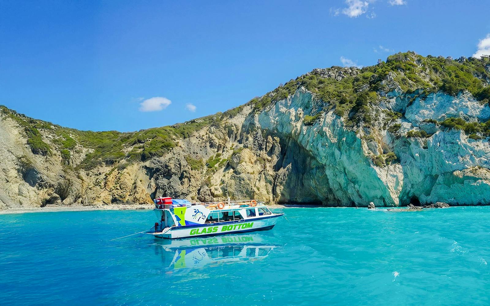 Glass bottom boat on turquoise waters near rocky cliffs in Zakynthos.