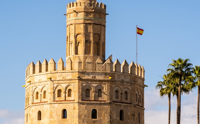 Torre del Oro with Spanish flag in Seville, part of a guided monumental walking tour.