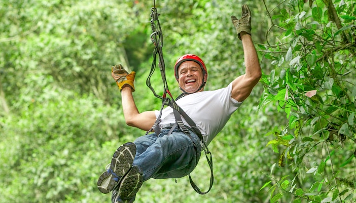 Person ziplining through lush forest at Waitomo Caves Zipline Park.