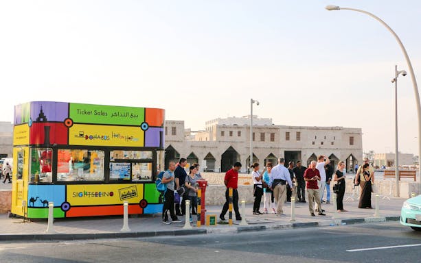 Doha Bus ticket kiosk with tourists at Souq Waqif, Qatar.