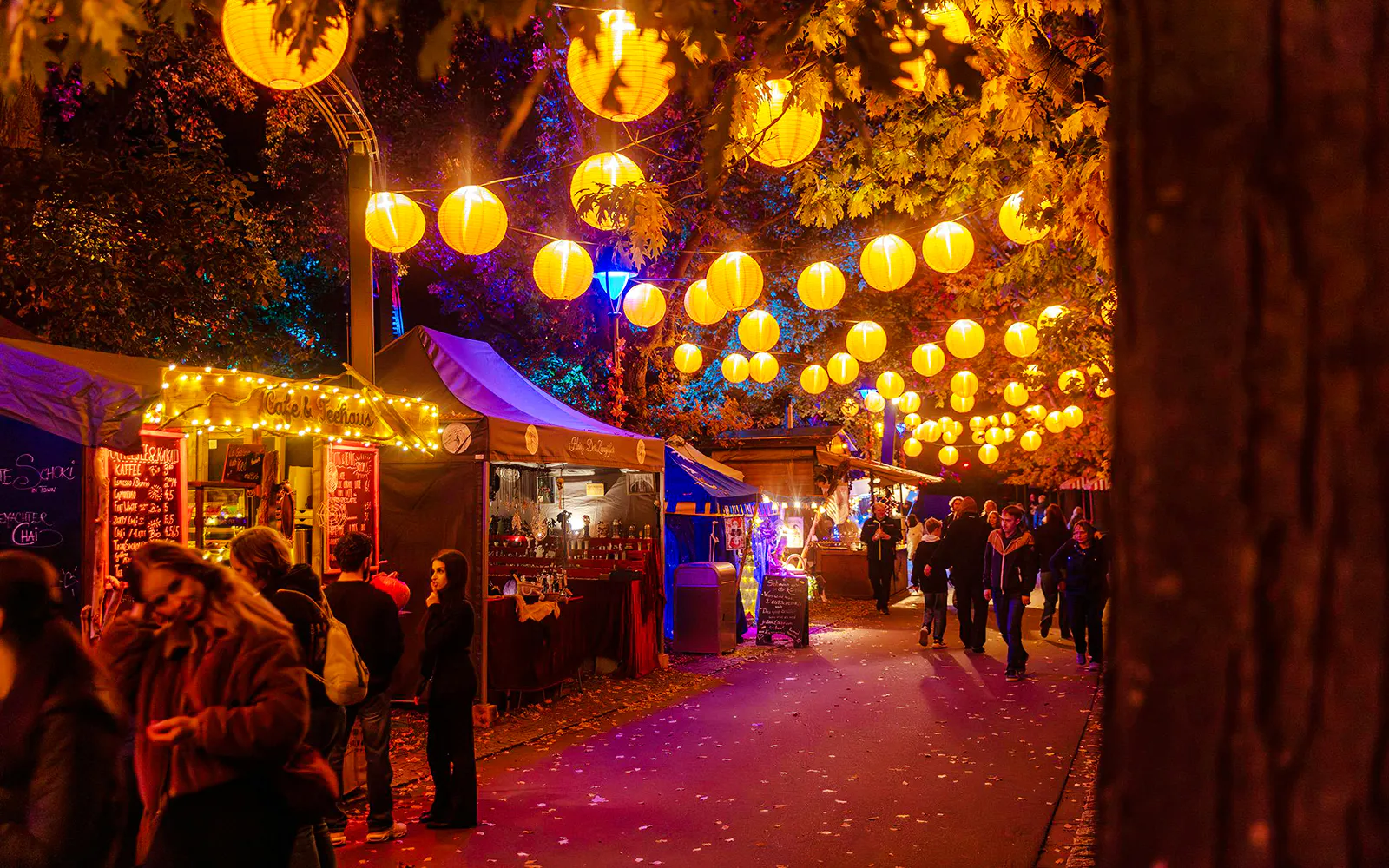 Heide Park Halloween market with lanterns and food stalls at night.