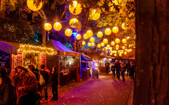 Heide Park Halloween market with lanterns and food stalls at night.