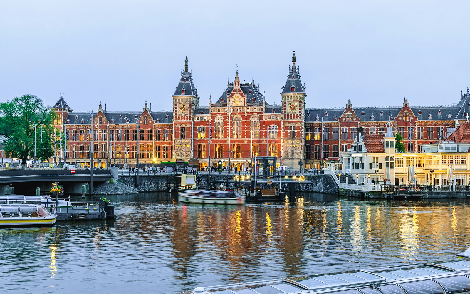 Amsterdam Centraal station with canal boats in North Holland, Netherlands.
