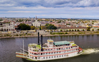 Riverboat cruising on the Mississippi River with New Orleans skyline in the background.