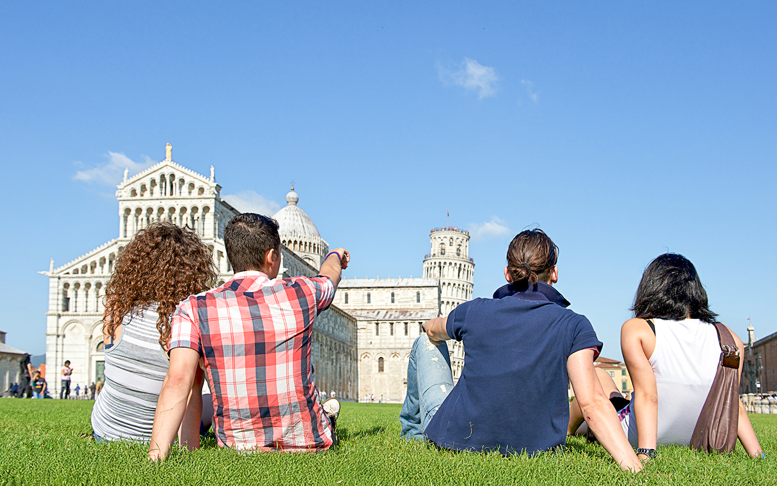 A group of friends relaxing and looking at the Leaning Tower of Pisa
