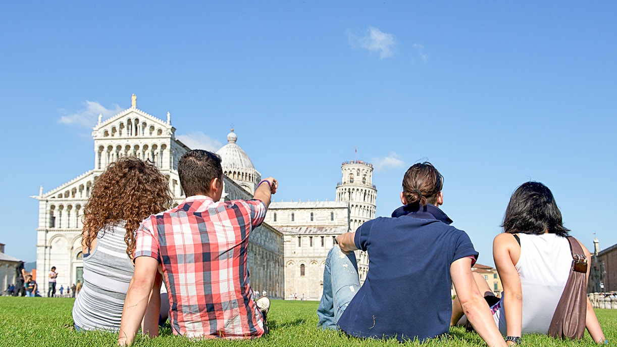 A group of friends relaxing and looking at the Leaning Tower of Pisa
