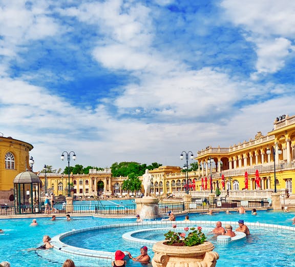 Visitors enjoying thermal pools at Szechenyi Bath, Budapest, with historic architecture in the background.