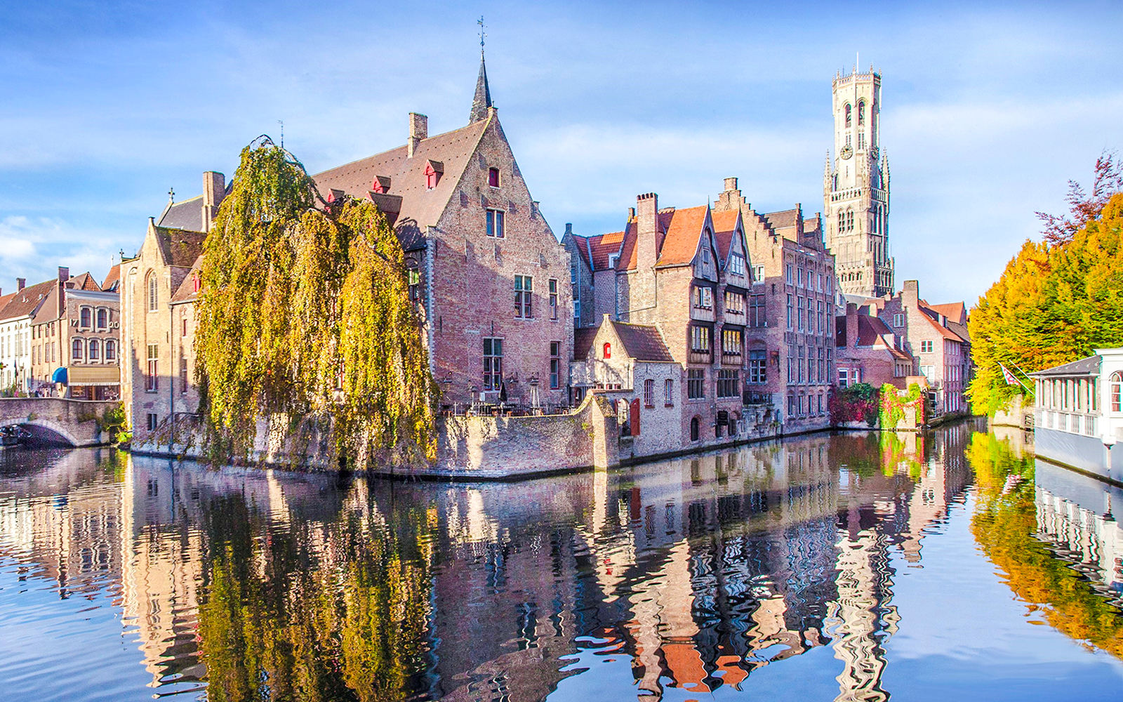 Rozenhoedkaai canal view with Belfry of Bruges tower in the background, Bruges, Belgium.