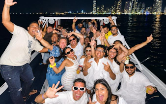 Group enjoying a lively sunset party cruise in Cartagena with city skyline in the background.
