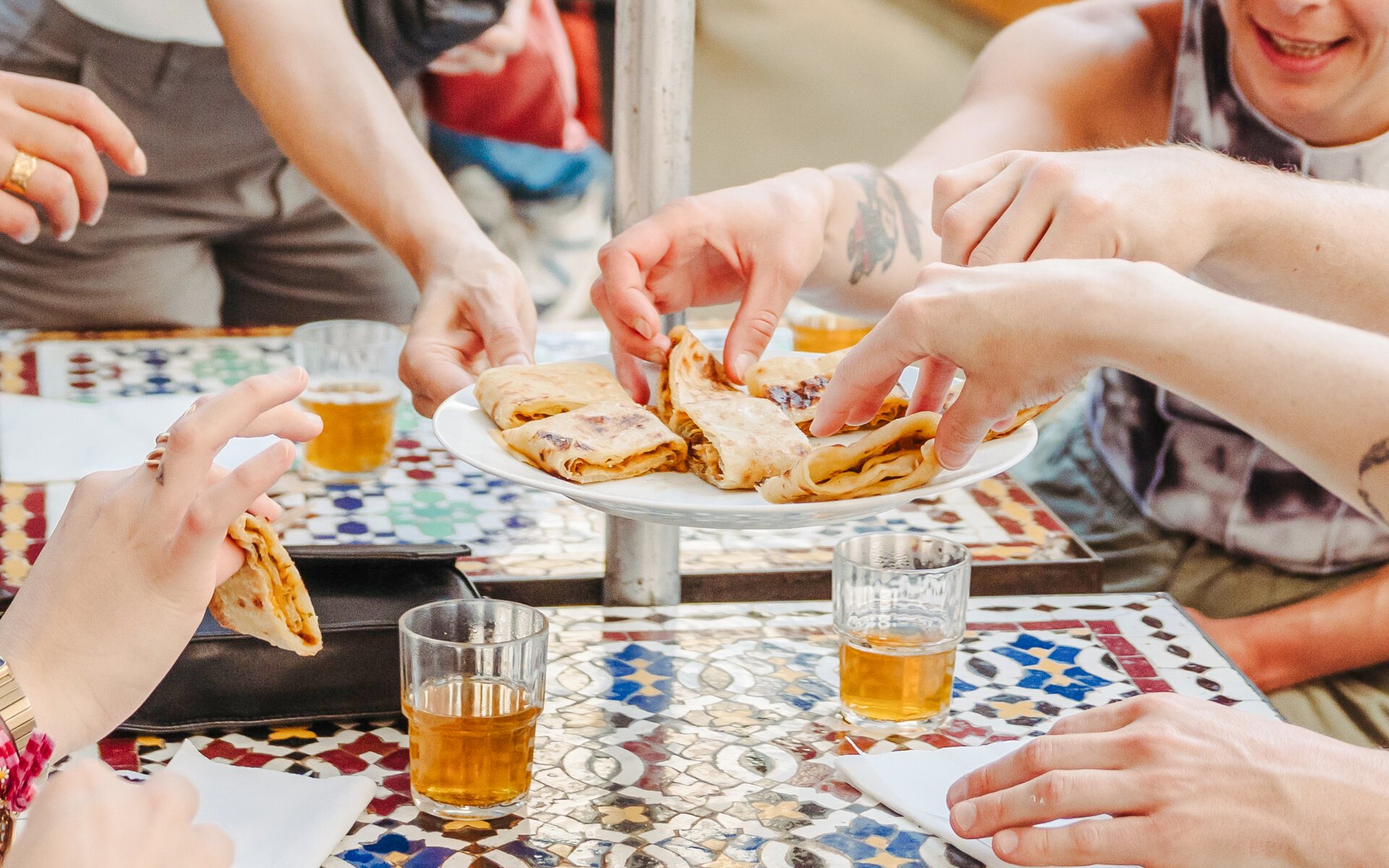 Hands reaching for crepes on a plate during the Ultimate Paris Food Tour.
