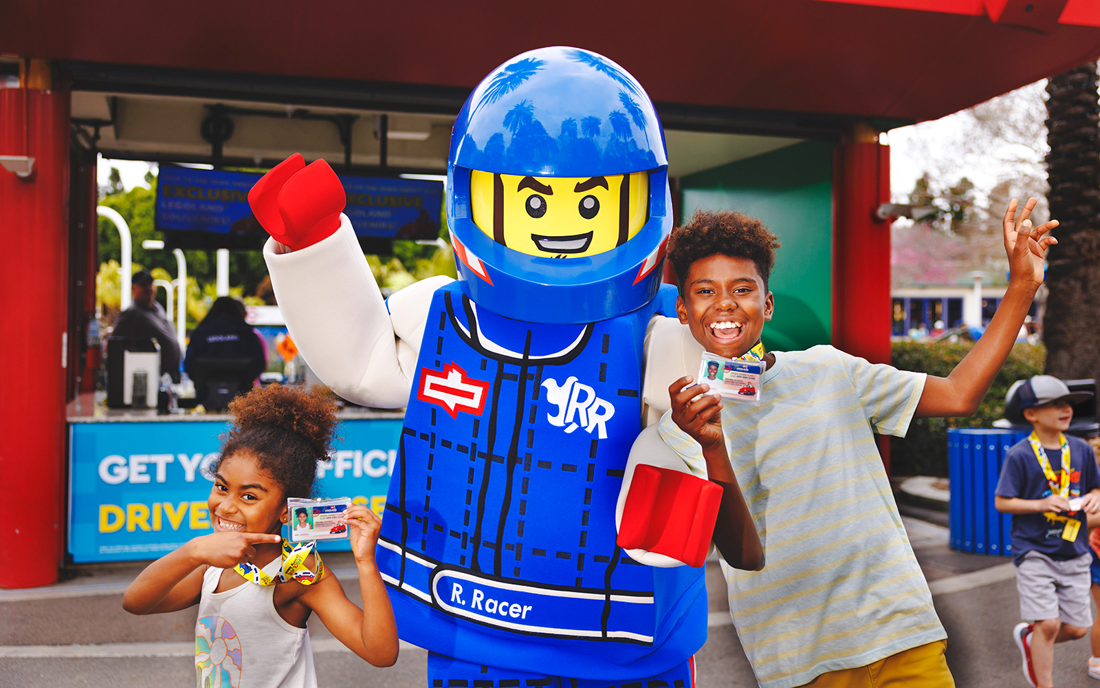 Kids holding LEGO driving licenses with a LEGO character at LEGOLAND® California.