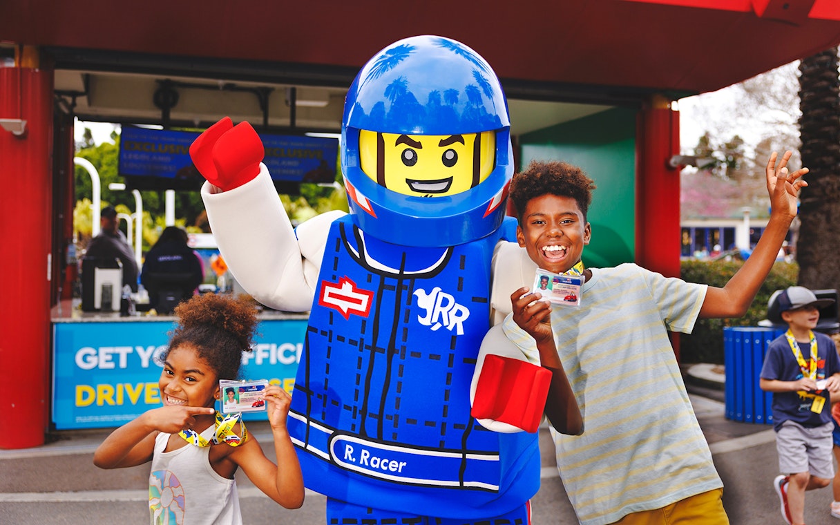 Kids holding LEGO driving licenses with a LEGO character at LEGOLAND® California.