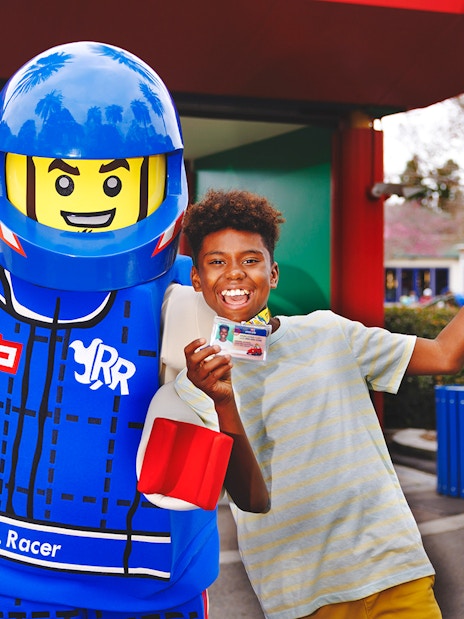 Kids holding LEGO driving licenses with a LEGO character at LEGOLAND® California.