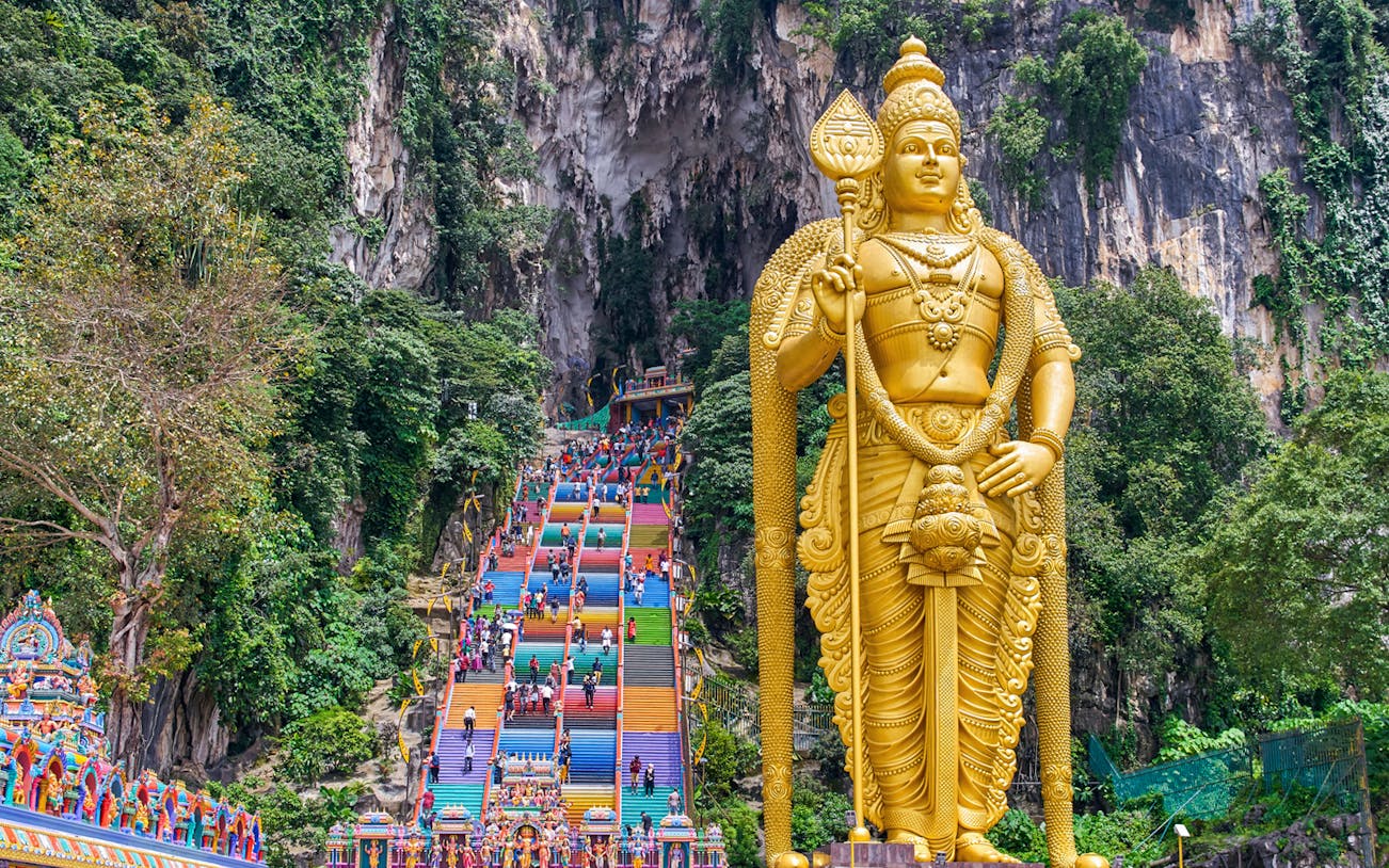Golden statue of Lord Murugan and colorful steps at Batu Caves, Kuala Lumpur.