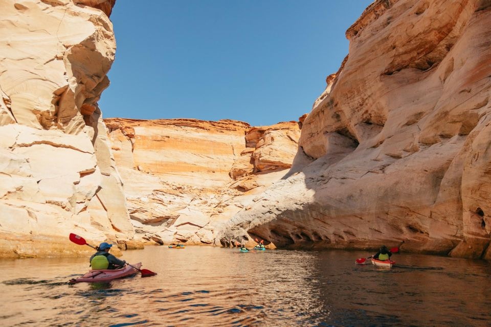 Kayakers navigating through Antelope Canyon on Lake Powell, surrounded by towering sandstone cliffs.