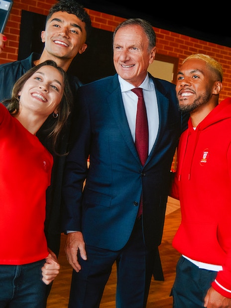 Group taking a selfie at Anfield with Liverpool Legends exhibit in background.