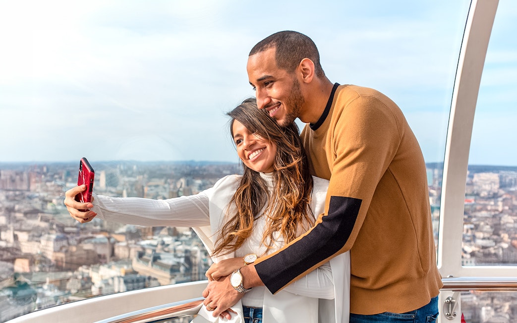 Visitors taking a selfie on the London Eye with cityscape views.