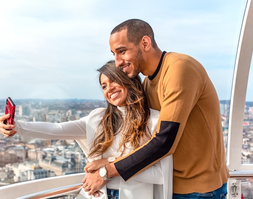 Visitors taking a selfie on the London Eye with cityscape views.