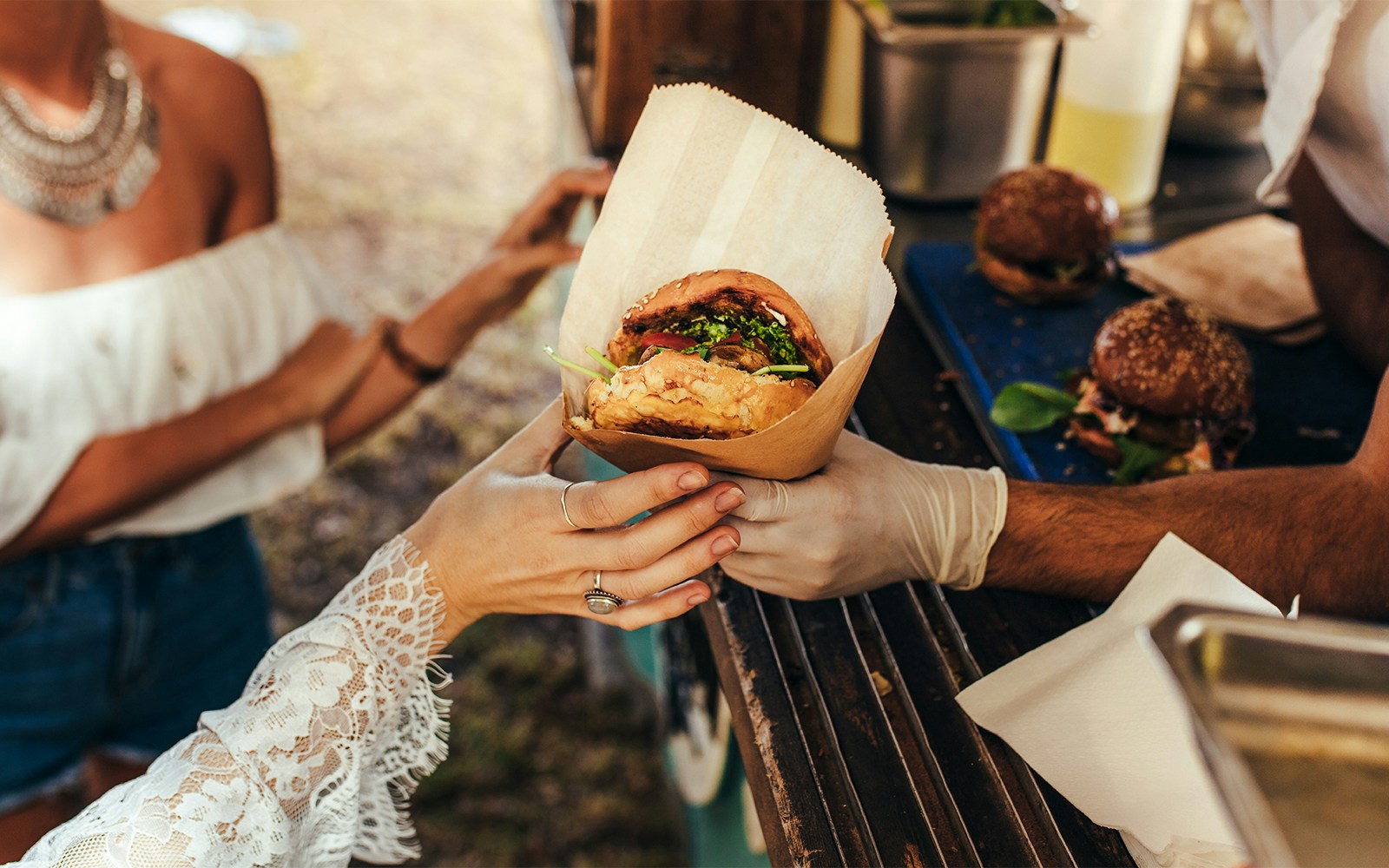Person receiving a burger from a food truck.