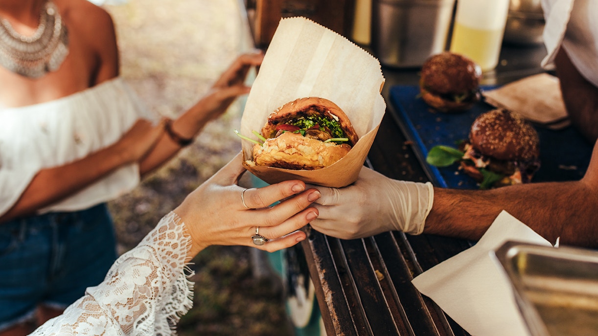Person receiving a burger from a food truck.