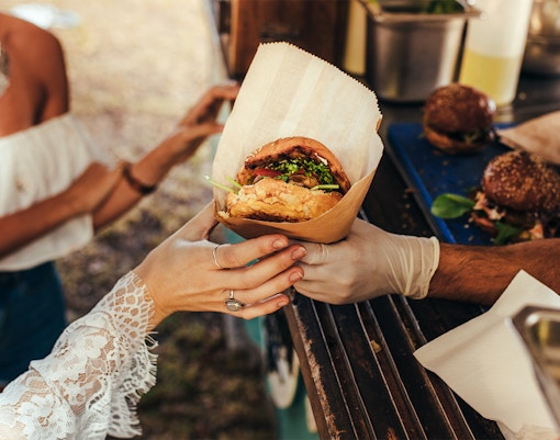 Person receiving a burger from a food truck.