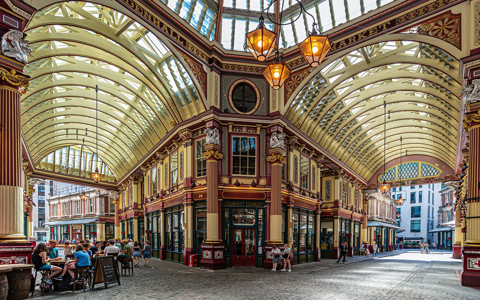 Leadenhall Market in London with people dining under ornate Victorian architecture.