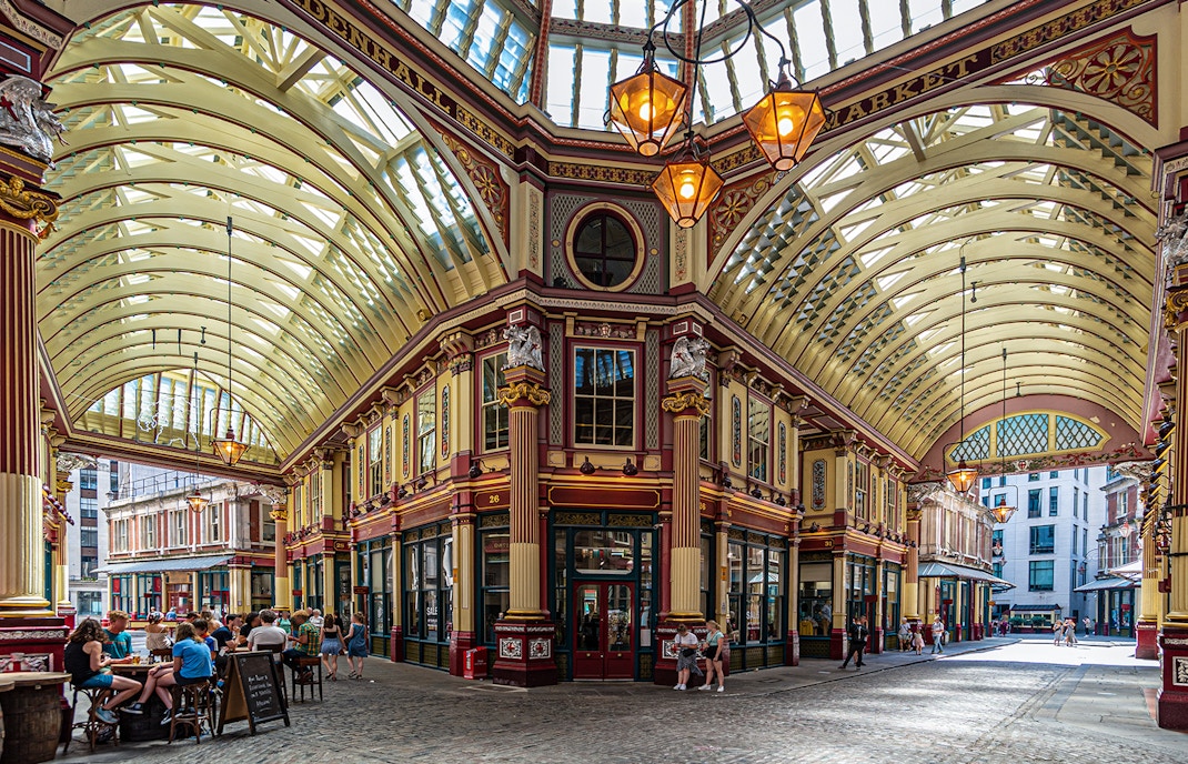 Leadenhall Market in London with people dining under ornate Victorian architecture.