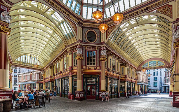 Leadenhall Market in London with people dining under ornate Victorian architecture.