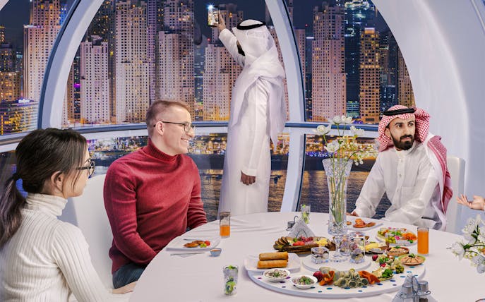 Guests dining inside AIN Dubai Wheel with city skyline view.