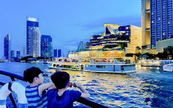 Yodsiam sightseeing boat with passengers on deck near Iconsiam, Bangkok skyline in background.