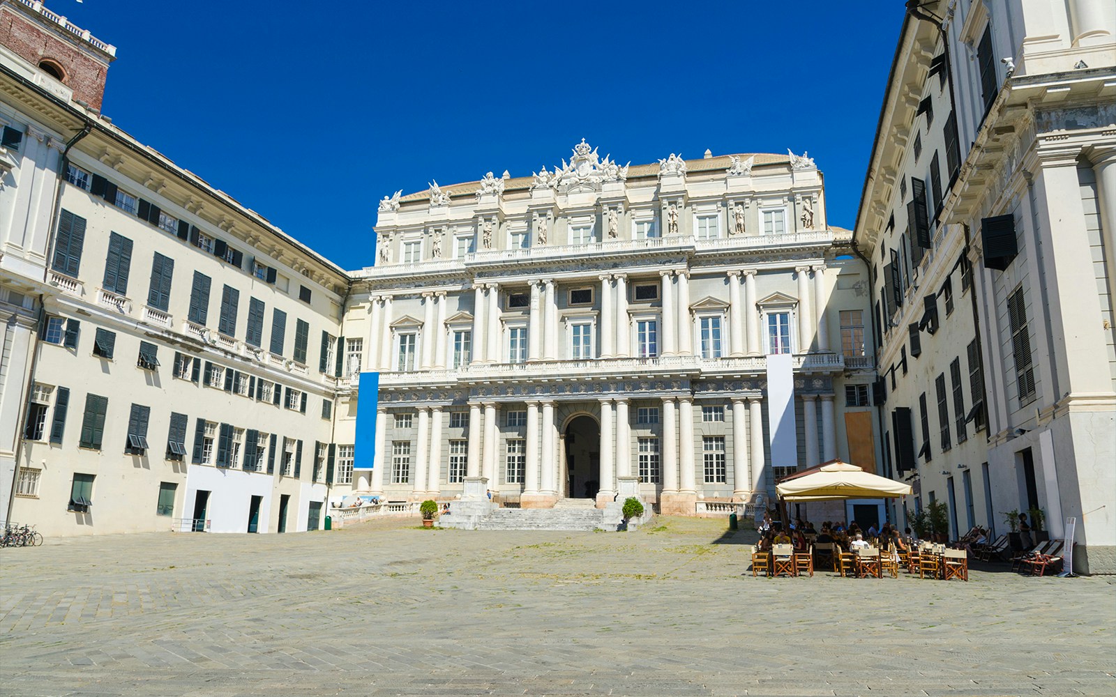 Piazza Matteotti Genoa bustling square with historic buildings and people enjoying outdoor cafes.
