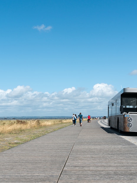 Tourist bus approaching Mont Saint-Michel, France, on a clear day.