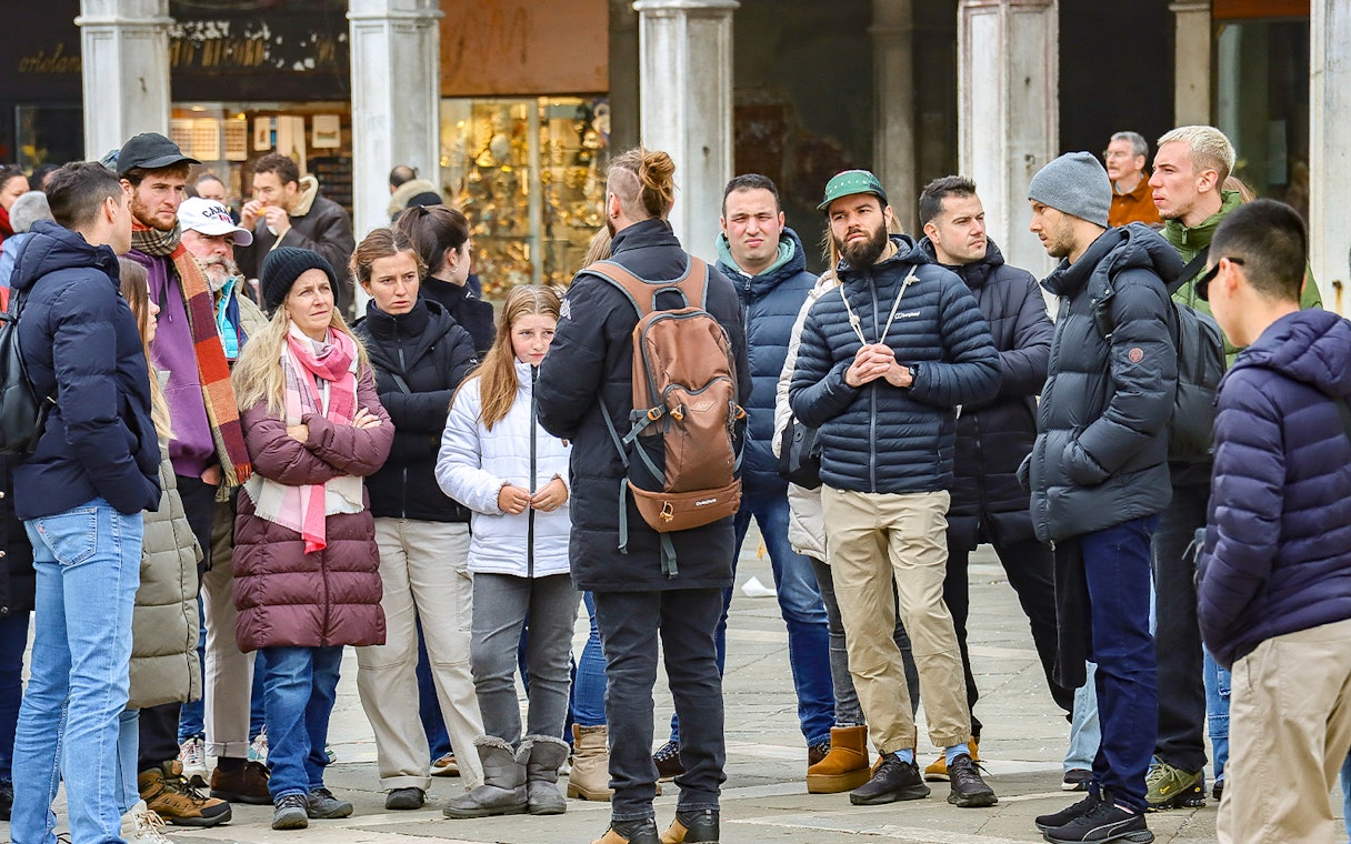Group of tourists listening to a guide during a walking tour in Venice.