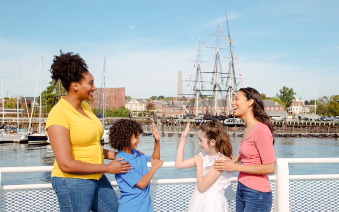 Guests enjoying the Historic Boston Harbor Cruise with a view of the USS Constitution.