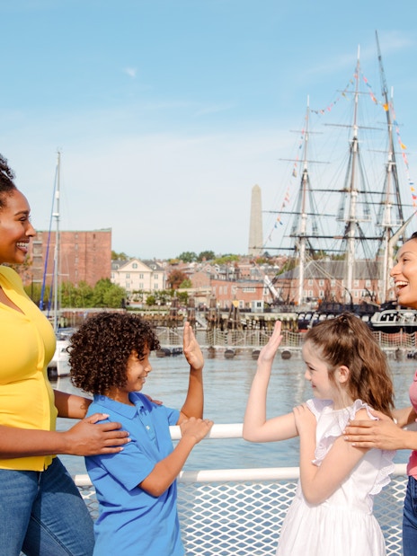 Guests enjoying the Historic Boston Harbor Cruise with a view of the USS Constitution.