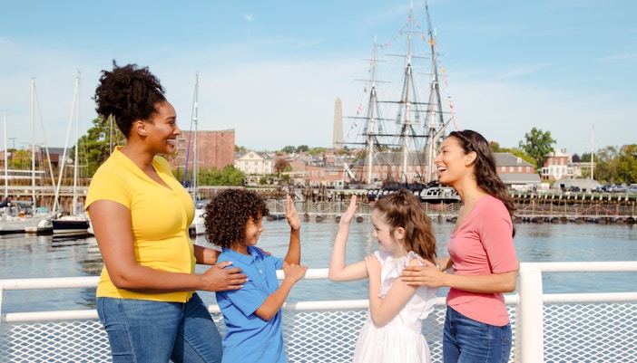 Guests enjoying the Historic Boston Harbor Cruise with a view of the USS Constitution.