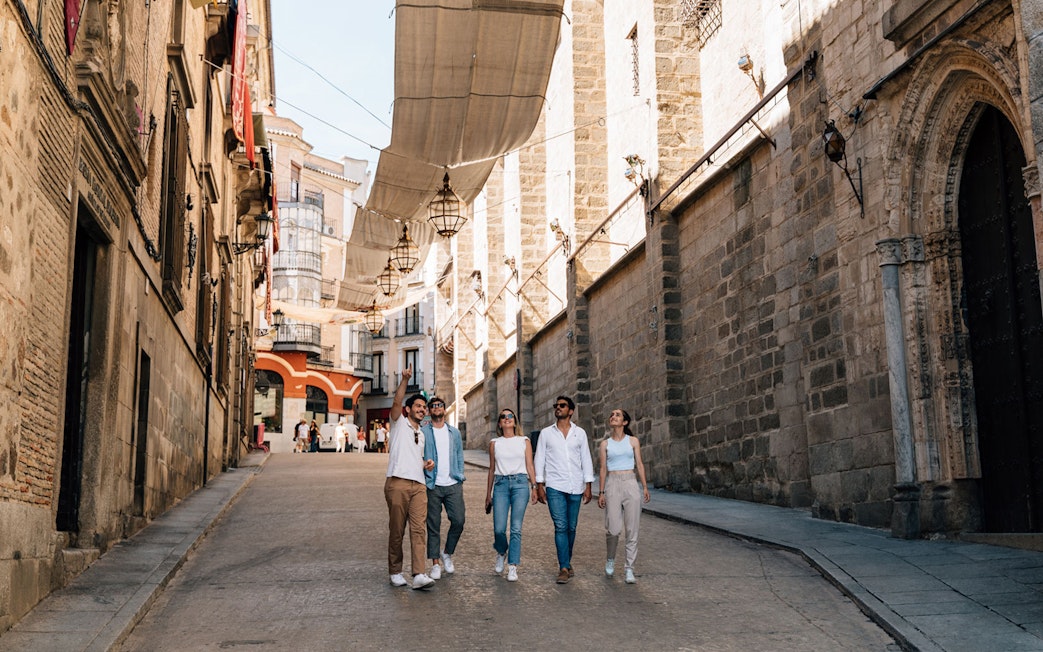 Tourists walking with a guide in Toledo's historic streets.