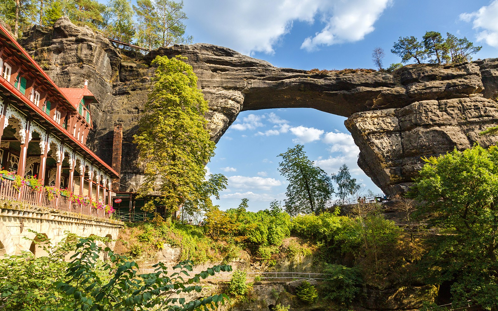 Pravcicka Brana rock arch with nearby historic building in Czech Republic.