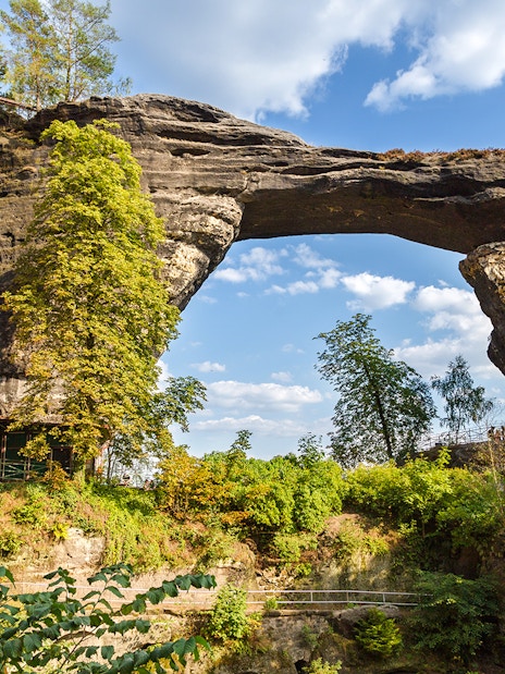 Pravcicka Brana rock arch with nearby historic building in Czech Republic.