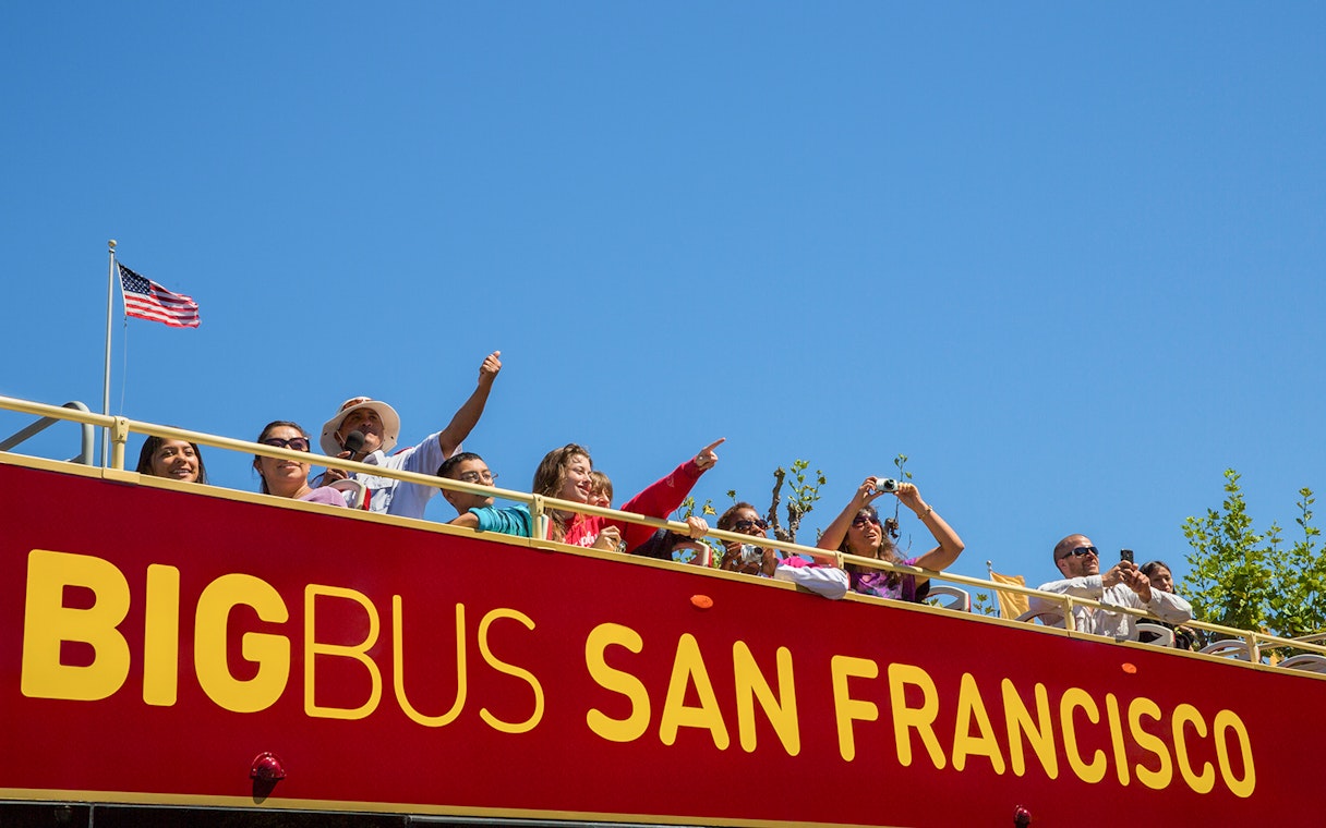 Tourists on a San Francisco hop-on hop-off bus enjoying city views.