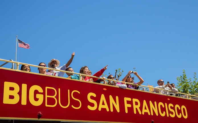 Tourists on a San Francisco hop-on hop-off bus enjoying city views.