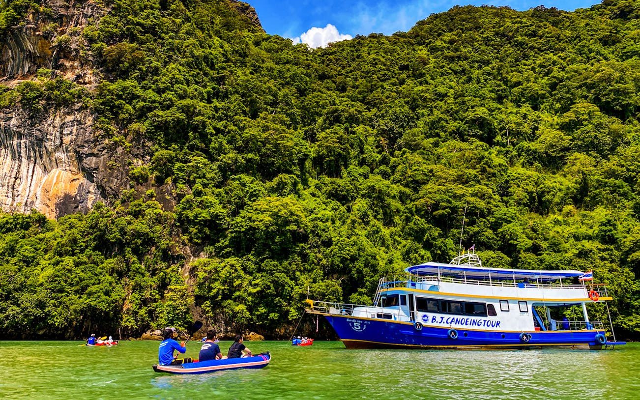 Tourists kayaking near limestone cliffs at James Bond Island, Phang Nga Bay, Thailand.