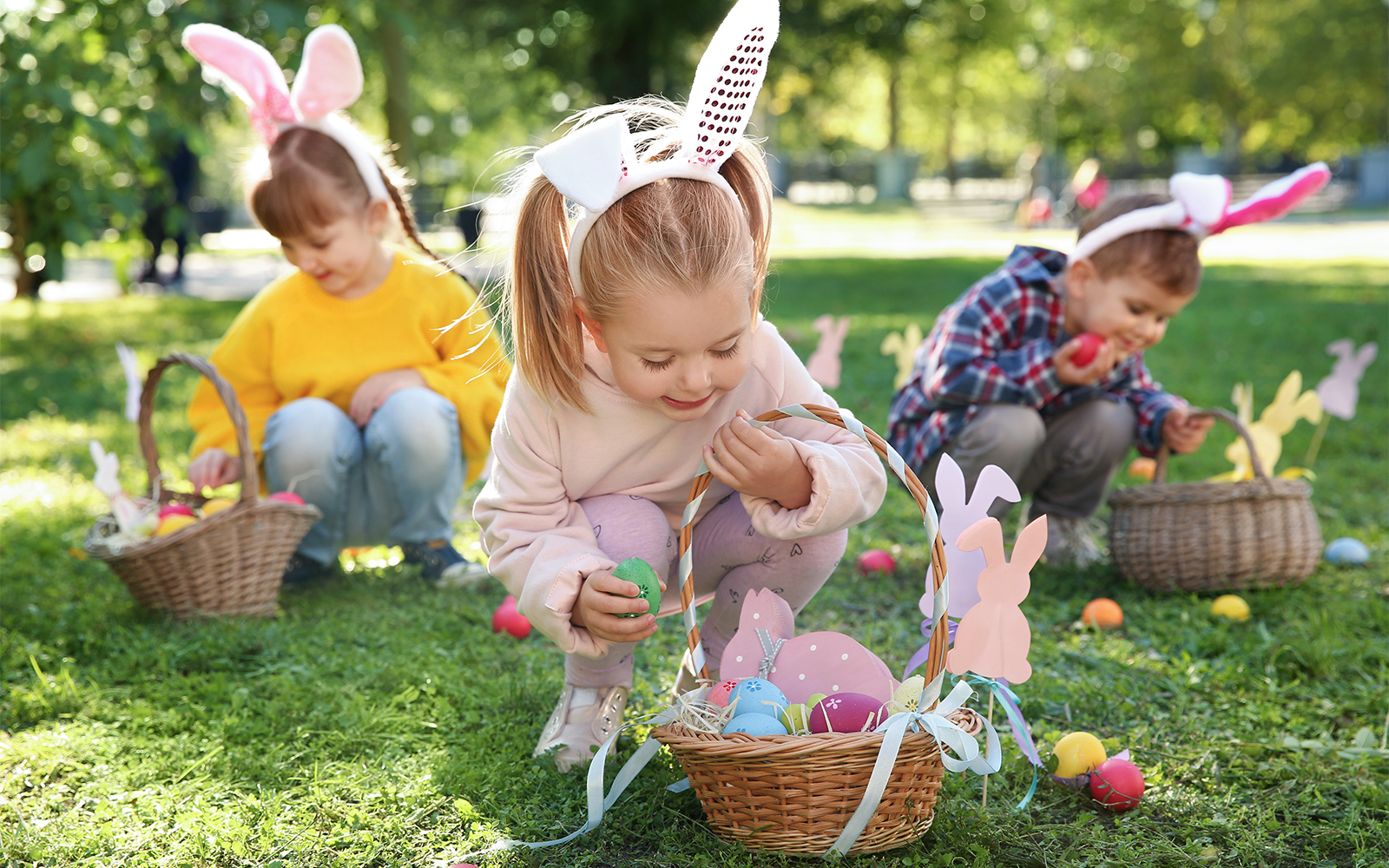 Children participating in an Easter egg hunt in a park, collecting colorful eggs in baskets.