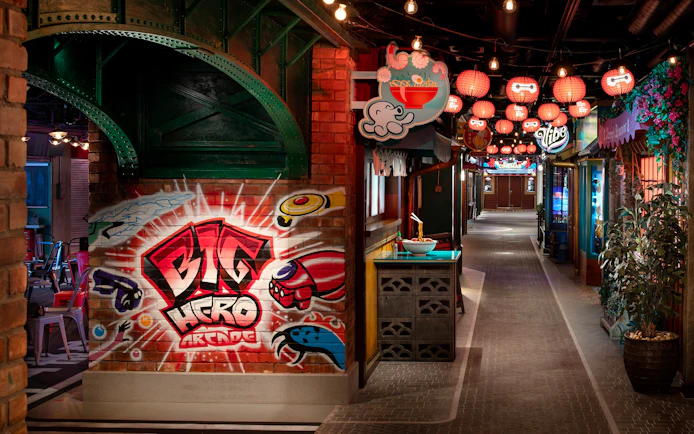 San Fransokyo street scene on Disney Cruise Line with Big Hero arcade mural and lanterns.